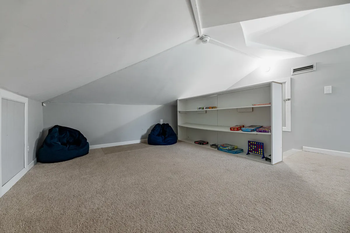 A cozy nook furnished with bean bag chairs, shelves lined with books and games, and a relaxed, inviting atmosphere. The space is clearly designed for both imaginative play and relaxing downtime, appealing to children and families alike.