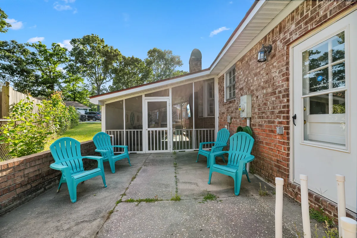 A cozy screened-in porch with turquoise chairs set against a brick wall, offering a comfortable space for morning coffee or evening relaxation. The porch suggests easy socializing and a connection to the outdoors.