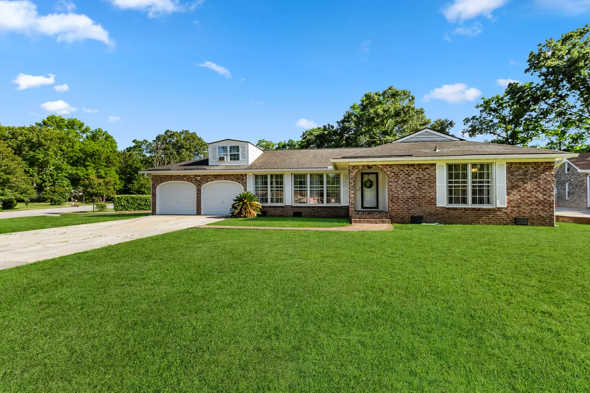 A welcoming exterior view of Southern Serenity, featuring a spacious front porch with large windows, a well-maintained lawn, and a driveway. Children can be seen playing in the yard while adults gather on the porch, creating an inviting and lively family setting.